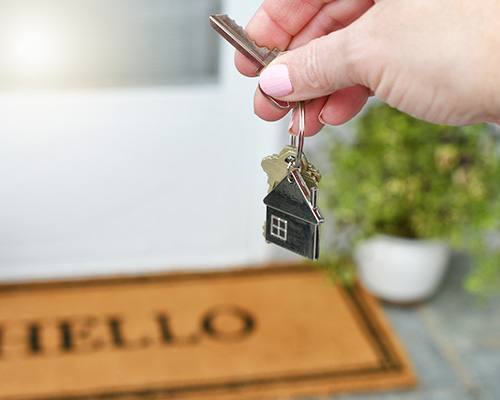 hand holding keys in front of house